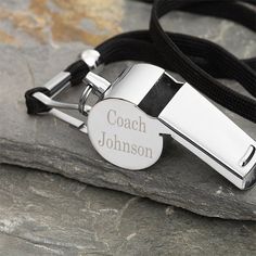 a black and white lanyard with a personalized bottle opener attached to it on a rock