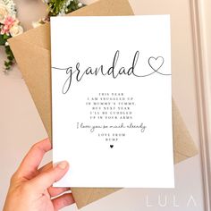 a hand holding up a card with the words grandad written in cursive writing