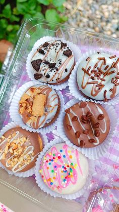 a plastic container filled with lots of different types of donuts on top of a table