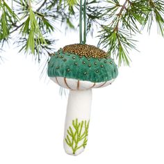 a green and white mushroom ornament hanging from a tree