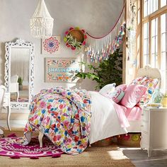 a bed room with a neatly made bed next to a desk and chair in front of a mirror