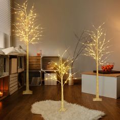 three lighted trees in the middle of a living room with white fur on the floor