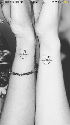 two people with matching tattoos on their wrists holding each other's hands together