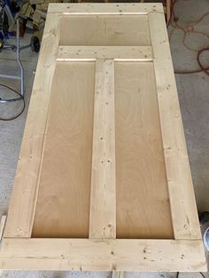 an unfinished wooden table with some tools on the ground