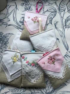 several pieces of cloth with embroidered flowers and lace on them are sitting on a table