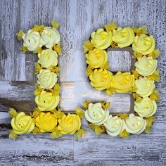 the letter b is made out of cupcakes with yellow flowers on it and sits in front of a wooden background