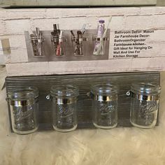 four glass jars with metal lids on display in front of a white brick wall and sign