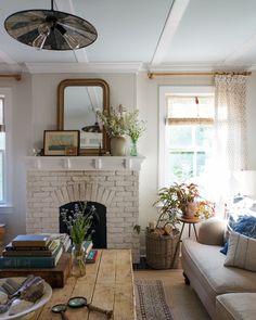 a living room filled with furniture and a fire place in front of a mirror on the wall