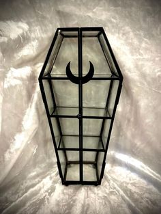 a glass lantern with a crescent on the top is sitting on a white sheeted surface