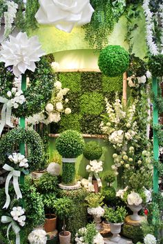 an arrangement of white flowers and greenery on display