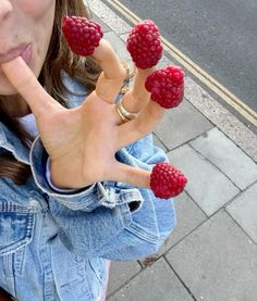 a woman with four raspberries on her fingers in the shape of a hand