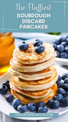 pancakes with blueberries and syrup are stacked on top of each other in the foreground