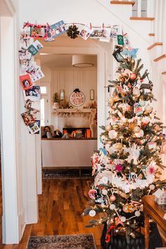 a decorated christmas tree sitting in the middle of a living room next to a staircase