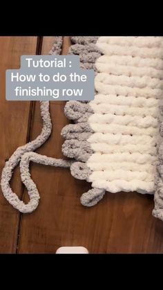 a white rug sitting on top of a wooden floor next to a cell phone and remote control