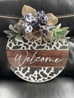 the welcome sign is made from wood and has a leopard print design on it, along with a burlap bow