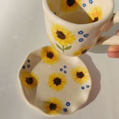 two sunflowers painted on the inside of coffee mugs, one being filled with water