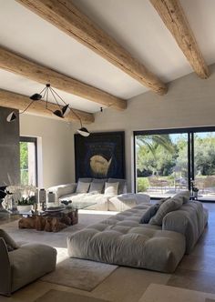 a large living room with lots of furniture and wood beams on the ceiling, along with sliding glass doors leading to an outdoor patio