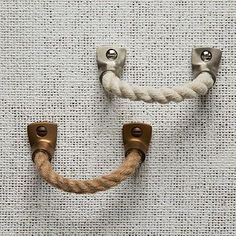 two metal handles with rope hanging from them on a white fabric wallpapered surface