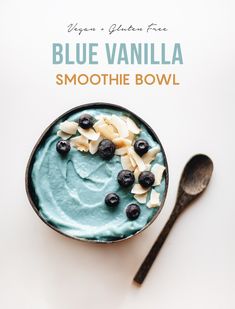 a bowl filled with blueberries and cream next to a spoon on a white surface