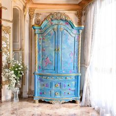 an ornate blue armoire with gold trimmings in a room filled with white curtains