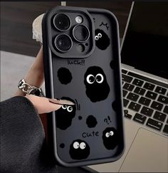 a person holding up an iphone case with eyes and noseballs on it in front of a laptop