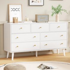 a white dresser in a room with pictures on the wall