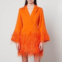 a woman in an orange dress with feathers on the skirt and jacket over her shoulders