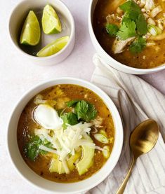 two bowls filled with soup and garnished with cilantro, limes, and sour cream