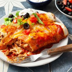 a white plate topped with enchilada covered in sauce