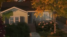 a small house with trees and bushes in the front yard at night, next to a sidewalk