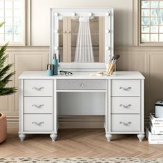 a white desk with drawers and a mirror on it next to a potted plant