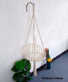 a white hanging chair next to a potted plant