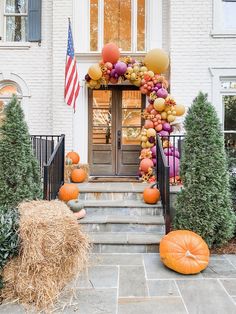 an entrance decorated with pumpkins, balloons and hay bales in front of a house