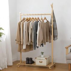 a clothes rack with several sweaters and shoes hanging on it next to a chair