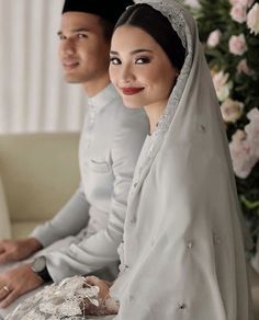 two people dressed in wedding attire sitting on a couch