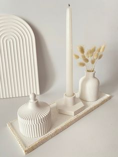 two white vases and a candle on a tray