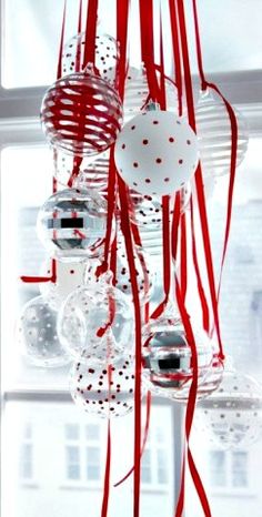 a bunch of ornaments hanging from the side of a window with red and white ribbons