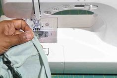 a person is sewing on a machine with their hand holding the fabric in front of them