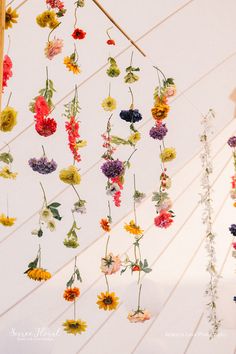 colorful flowers hanging from the ceiling in a tent