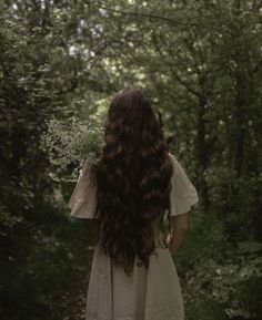 a woman with long hair standing in the woods looking back at her body and head