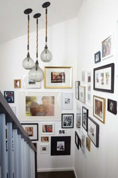 a staircase with many pictures on the wall and framed photos hanging up against the wall