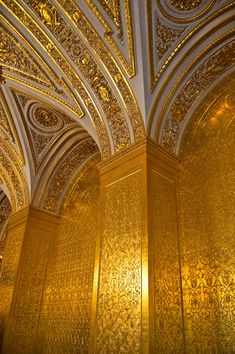 an ornately decorated room with gold walls and ceiling tiles in the middle of it