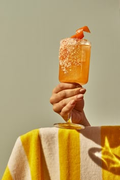 a person holding an orange drink in their hand