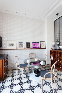 a dining room with black and white tile flooring, two chairs and a round glass table