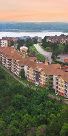 an aerial view of several multi - story buildings in the foreground, with trees and water in the background