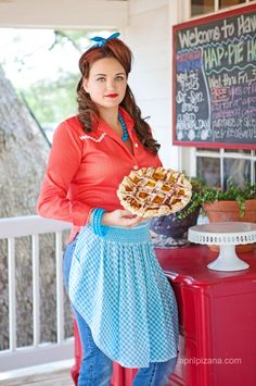 a woman in an apron holding a pie