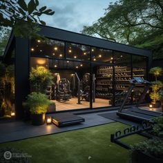 a home gym is lit up at night with lights on the windows and plants in pots