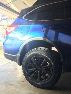 a blue car parked in a garage next to another vehicle with its tire on the ground