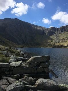 a lake surrounded by rocks and mountains under a blue sky