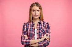 a woman in plaid shirt and tie standing with her arms crossed looking at the camera